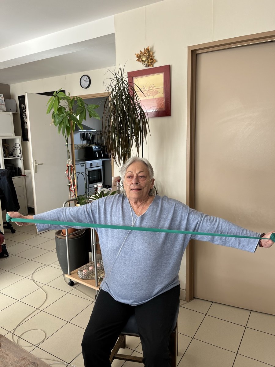 Patiente réalisant des exercices respiratoires avec élastique lors d'une séance APA